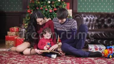 圣诞屋。 一家人围着一棵新年树聚在一起。 那孩子手里拿着书。 小心的父母读